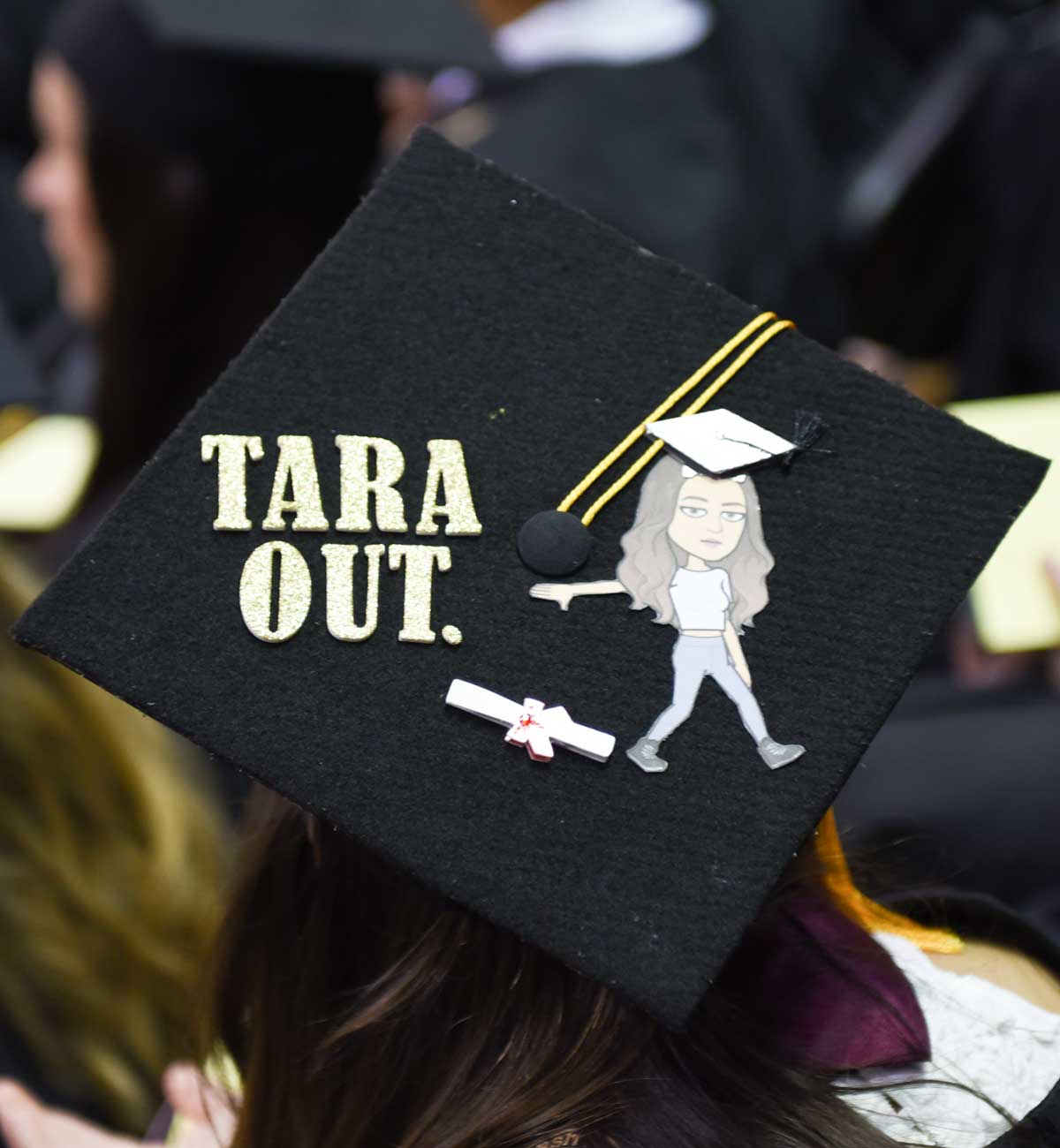 Grad cap decorated with text: Tara Out and image of person dropping diploma