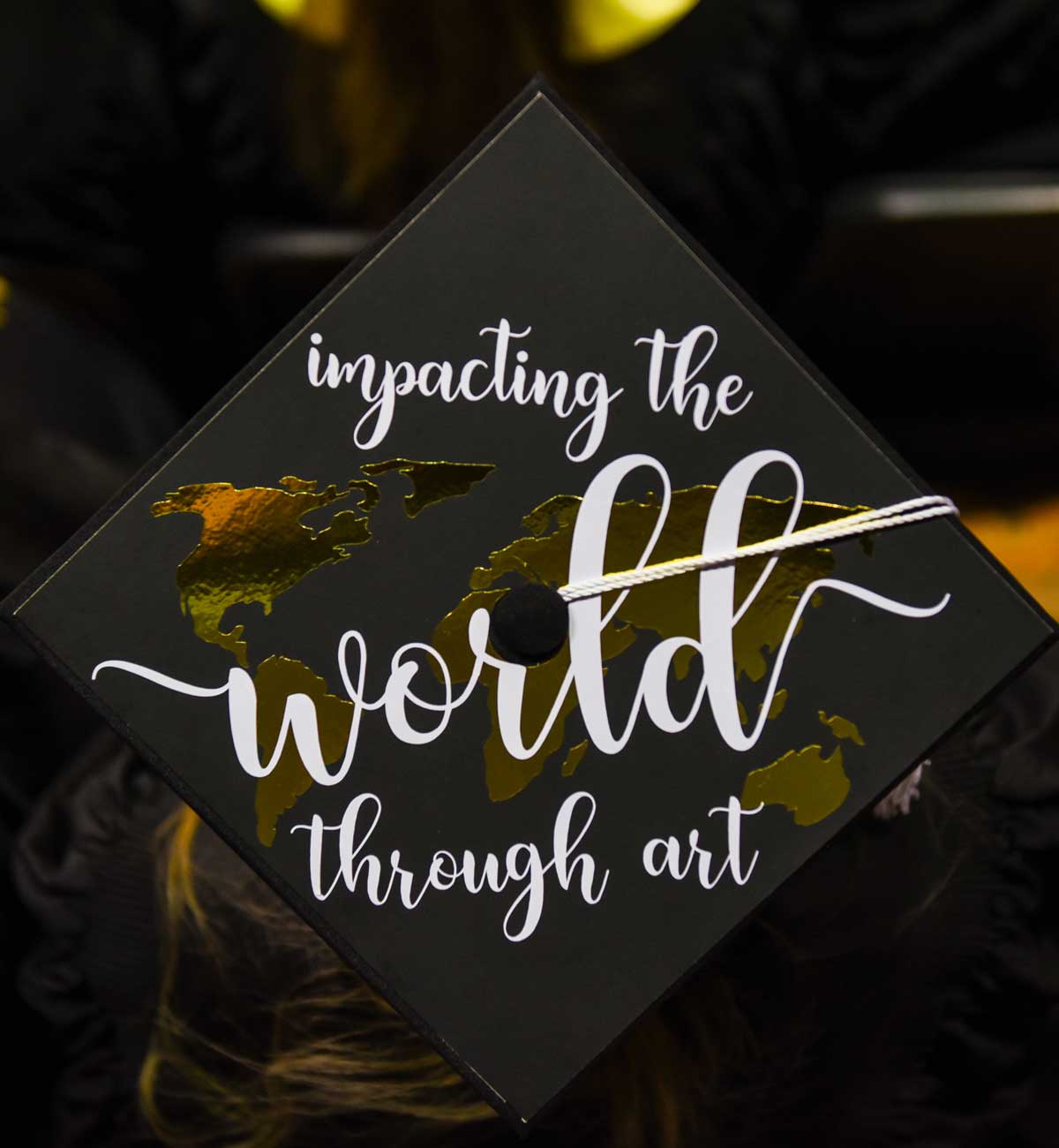 Grad cap decorated with text: Impacting the world through art