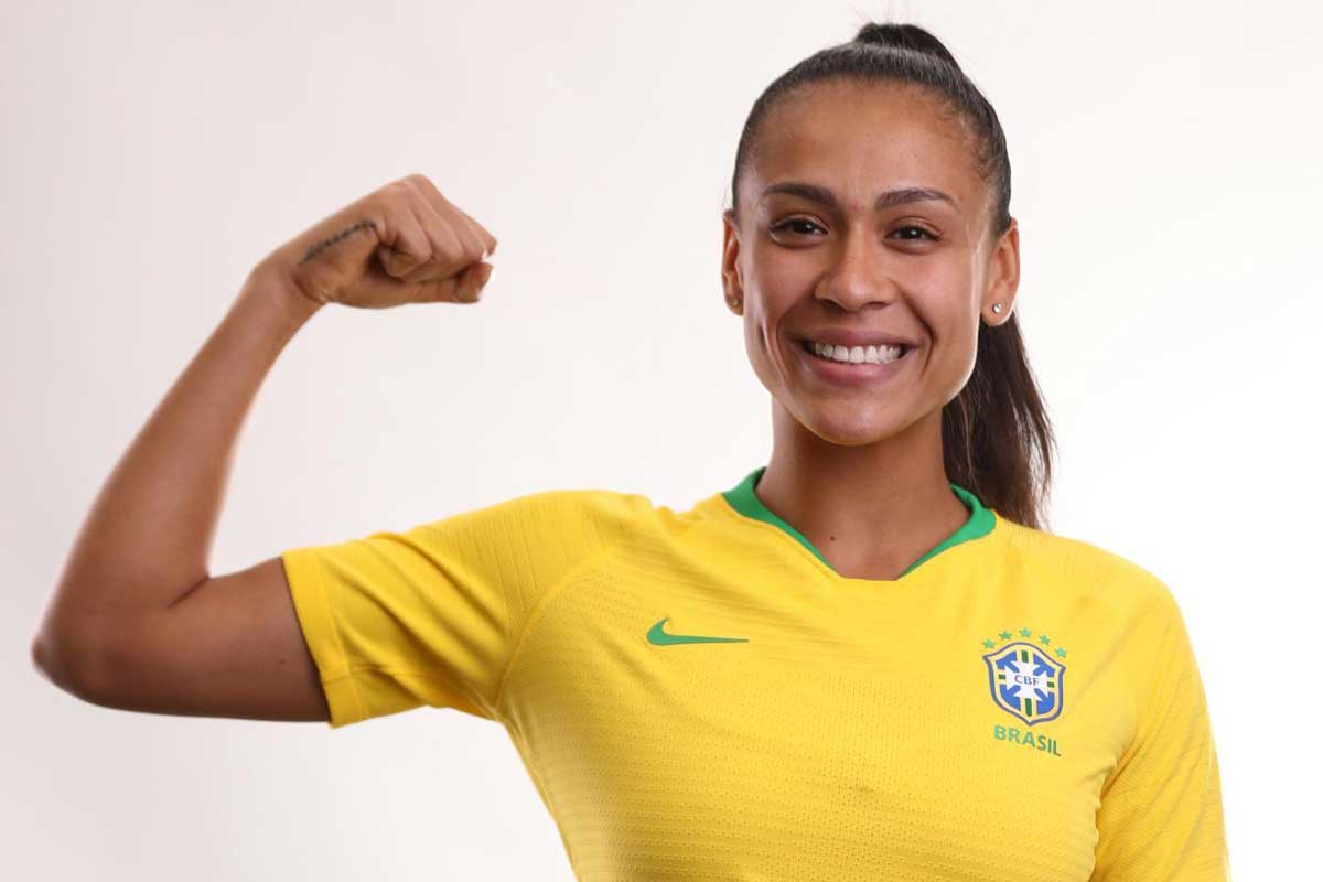 Female soccer player flexes muscle while wearing yellow jersey