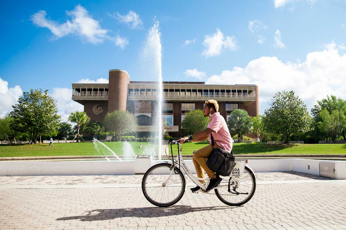 Man rides a bike near a fountain