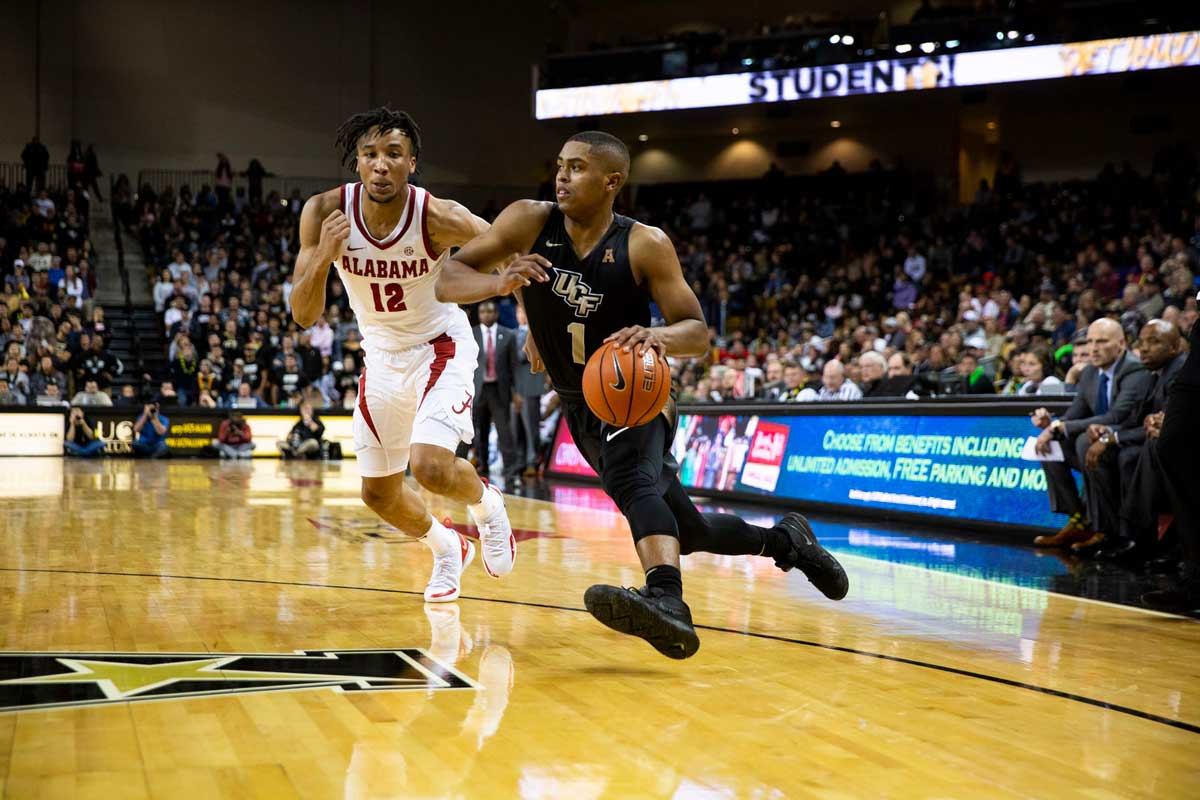 UCF basketball player BJ Taylor dribbles by Alabama defender