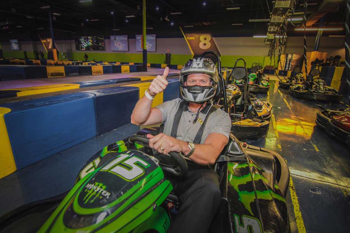 man gives thumbs up while seated in green go kart