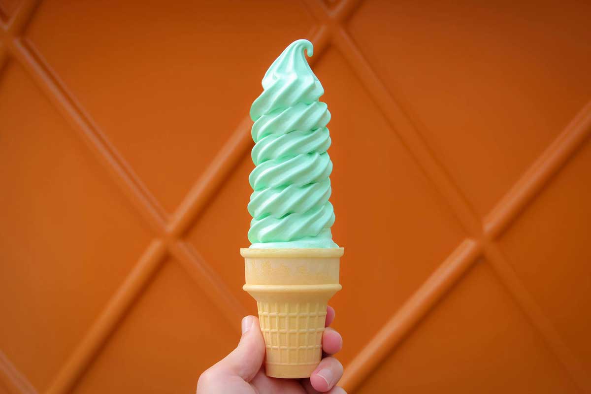 green softserve ice cream piled high on cake cone