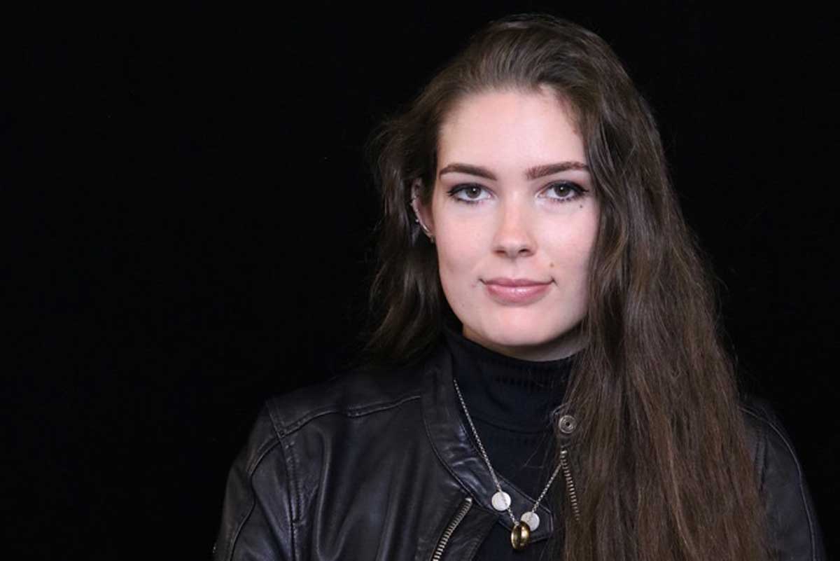 Brunette woman wearing black jacket and black turtleneck shirt