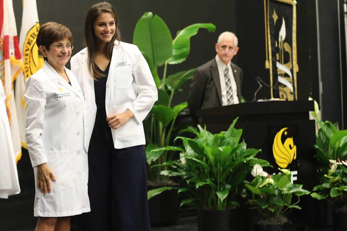 Lisvet Luceno stands on stage next to College of Medicine Dean Deborah German
