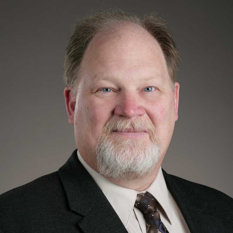 Headshot of a man wearing a suit and tie