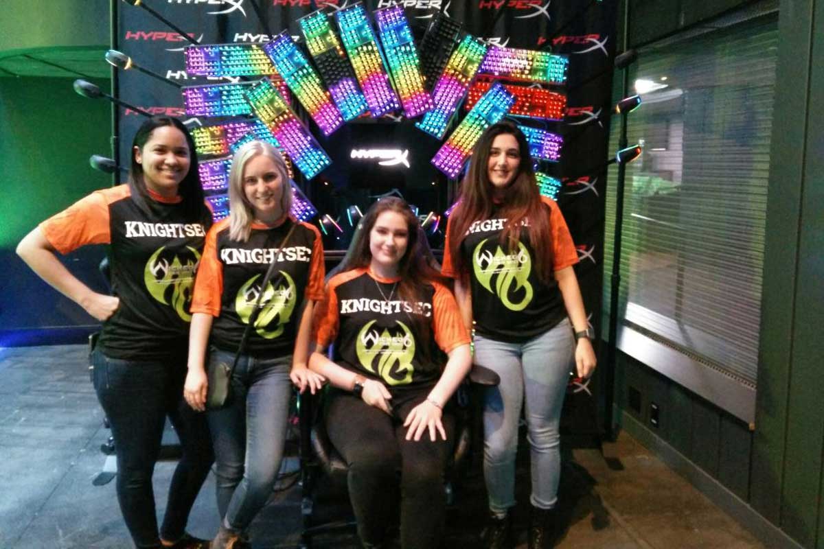 Group of four women pose in front of rainbow colored screen