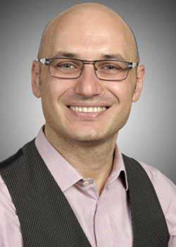 Man wearing glasses and vest with pink shirt