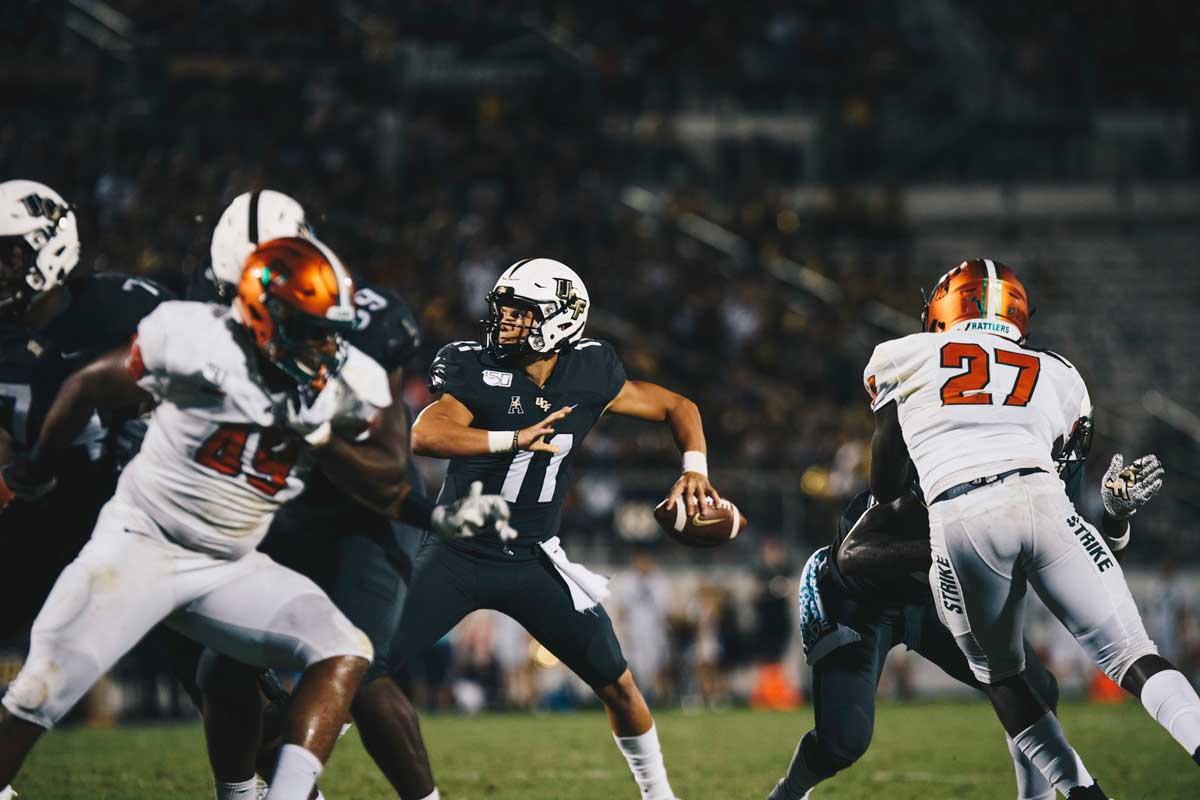 Freshman quarterback Dillon Gabriel cocks arm to throw football with offensive line blocking for him