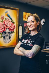 Nipple tattoo artist Stacie Becker stands with her arms folded in her studio Empower Tattoo