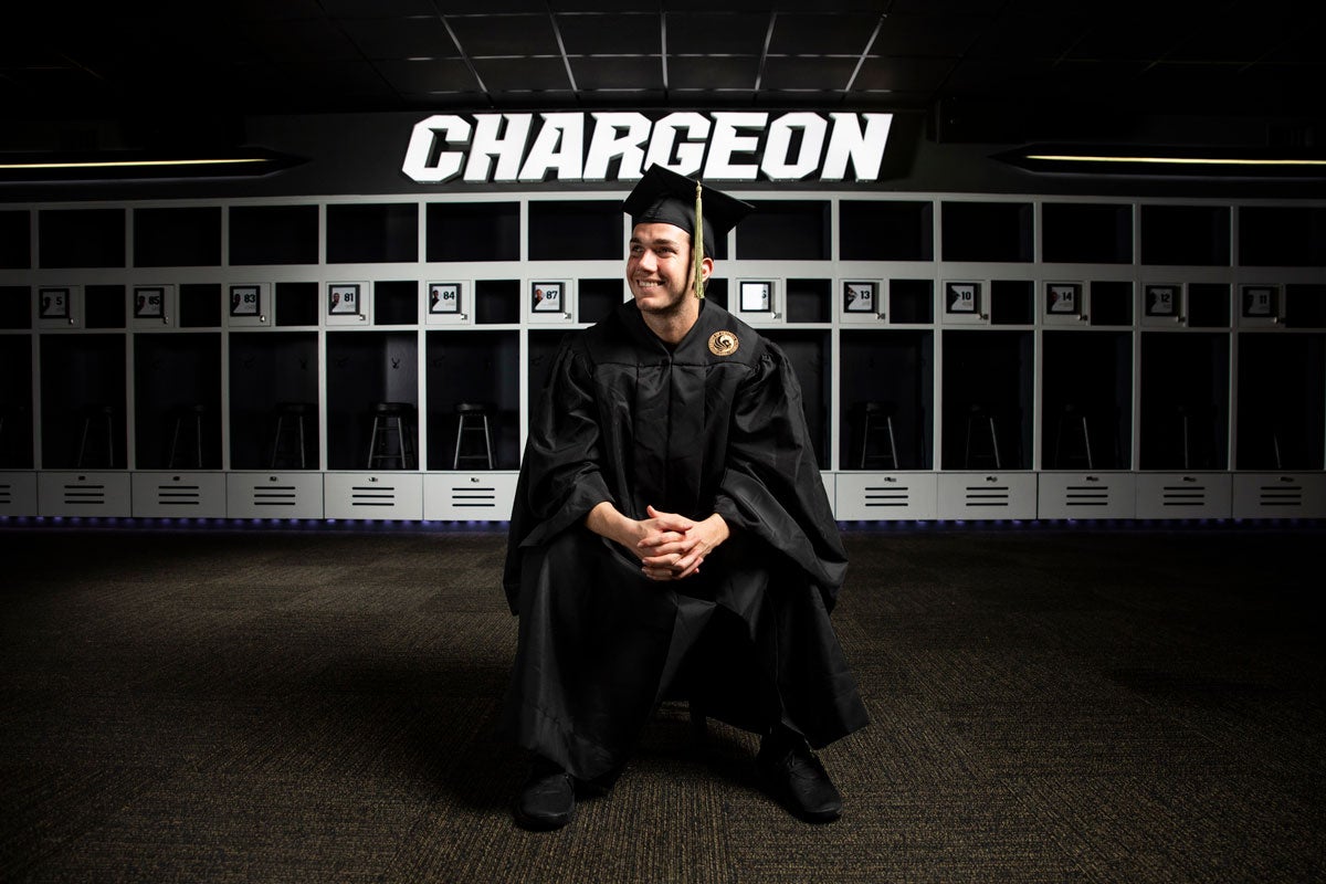 McKenzie Milton wears a cap in gown in the UCF football locker room.