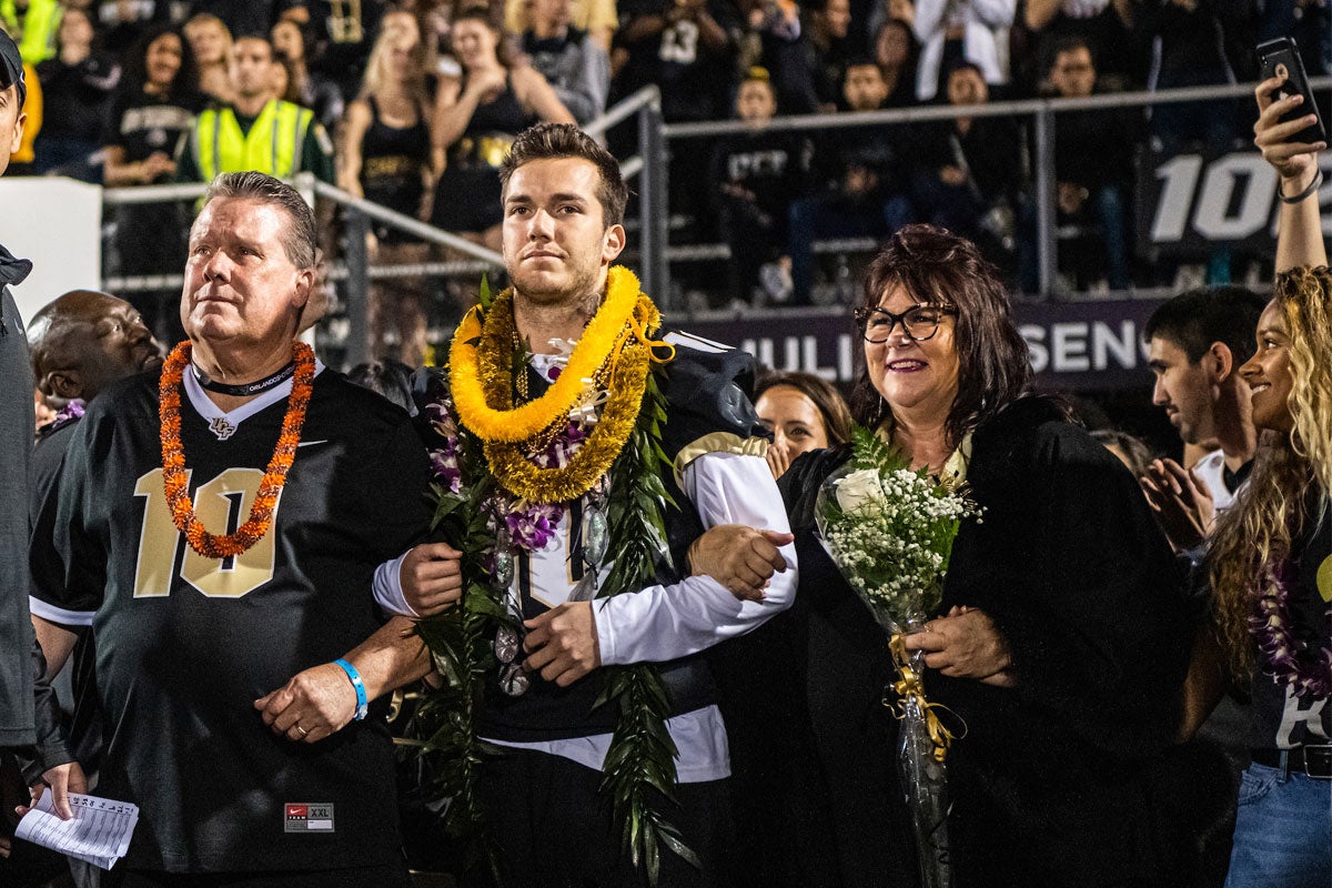 McKenzie Milton walks onto the field arm and arm with his mom and dad