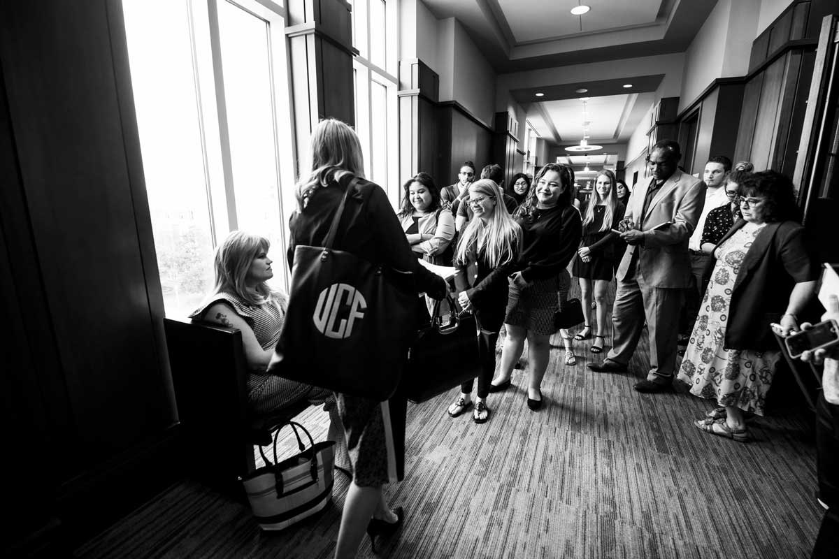 UCF students gather in a hallway as Juleigh Mayfield sits by a window