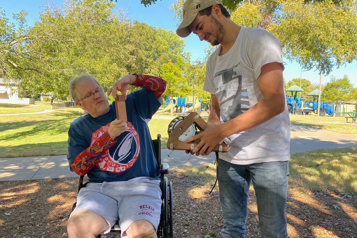 Juan Vila shows electric wheels to man sitting in wheelchair 