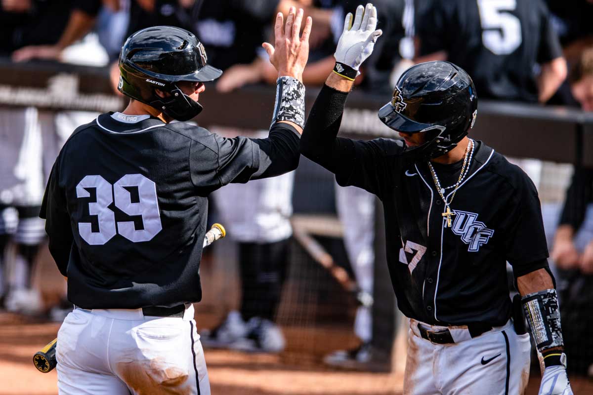 Two UCF baseball players give each other high fives near dugout