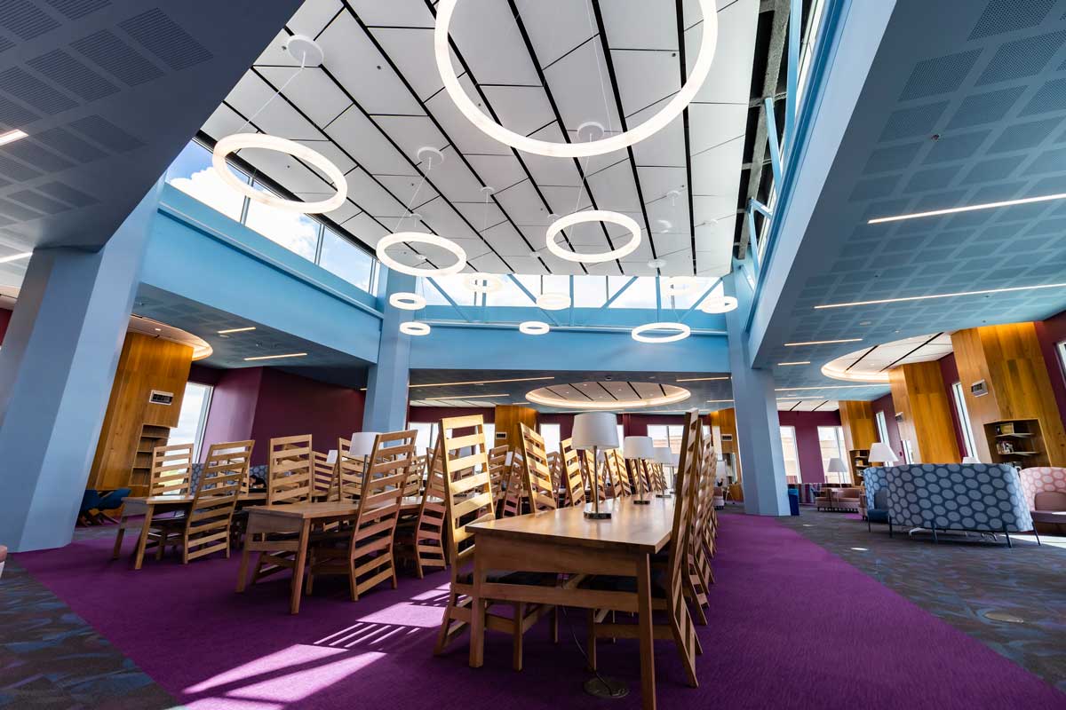 4th floor of Library featuring purple carpet, long wooden tables and chairs and circle lights