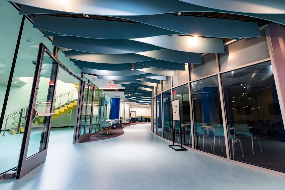 empty hallway with glass enclosed rooms and yellow staircase in the background