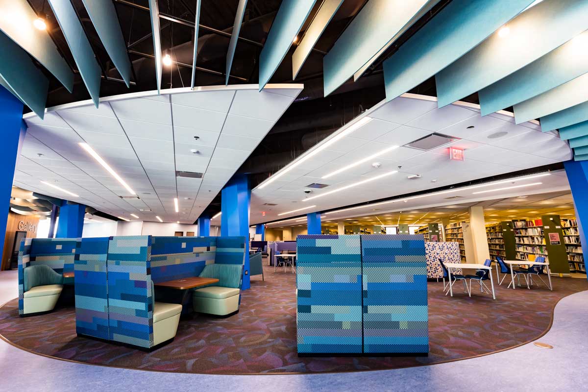 Blue high back chairs and tables on open floor with stacked bookshelves to the right