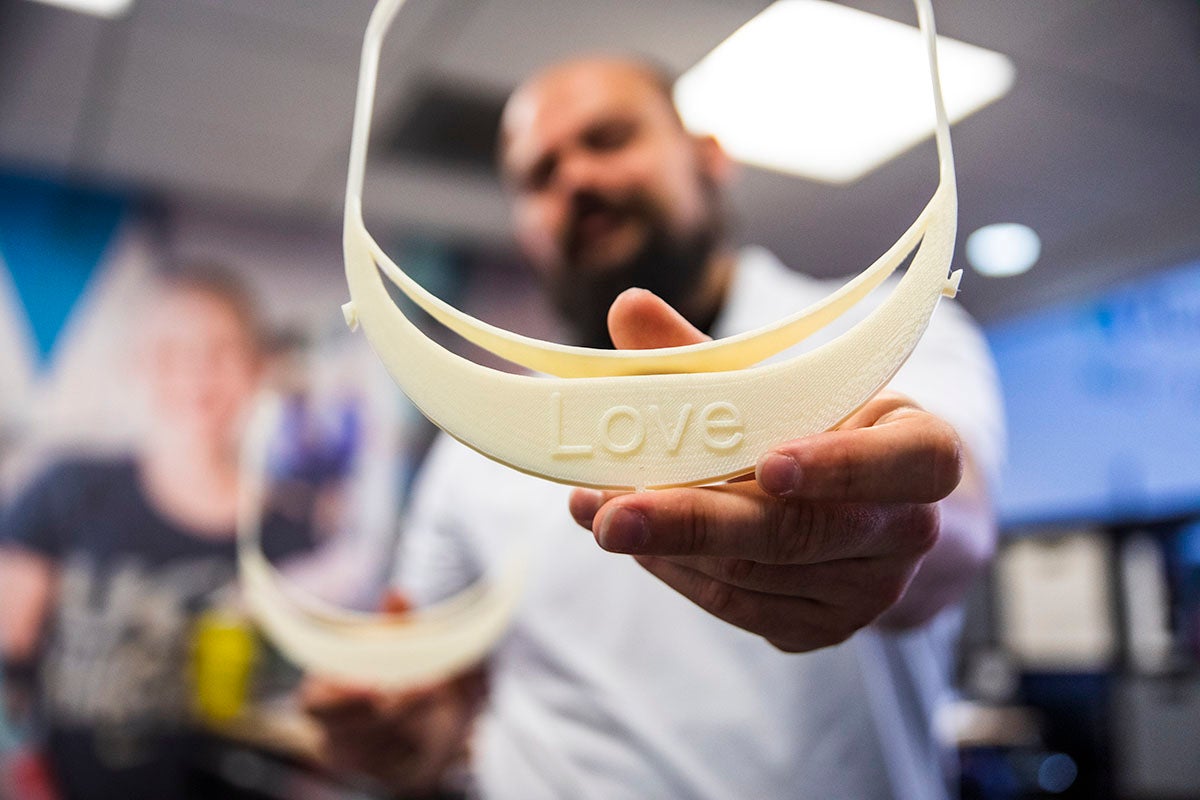 closeup of white 3D-printed visor with message "Love" etched in bill