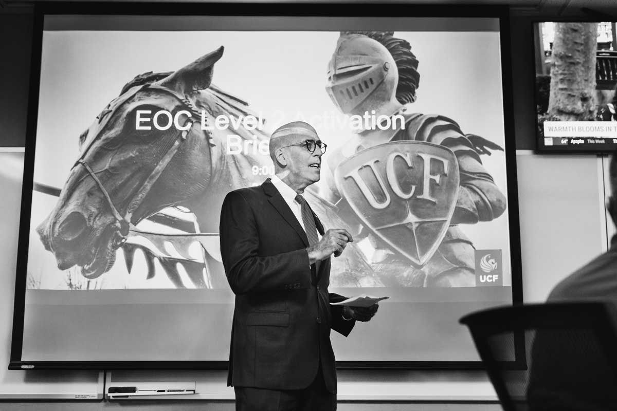 black and white photo of UCF Interim President Thad Seymour Jr. standing in front of a powerpoint screen