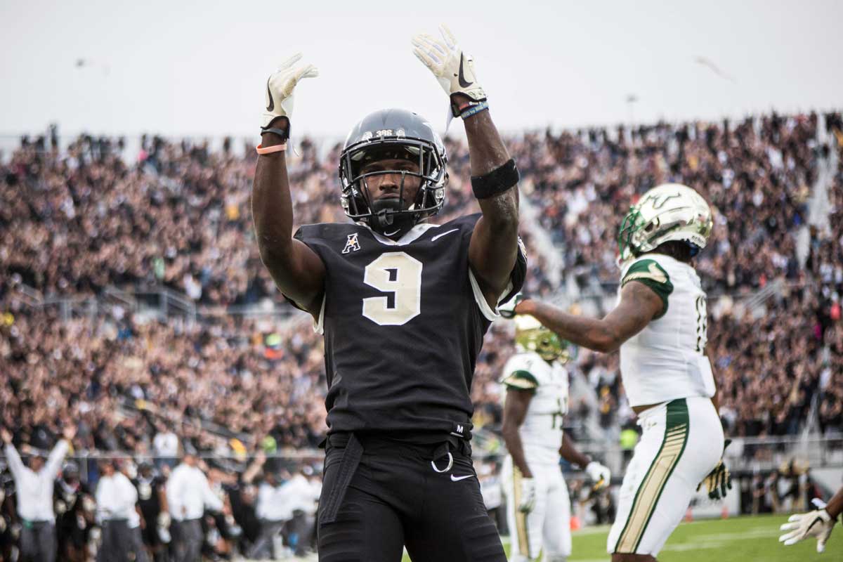 Adrian Killins Jr. in black uniform waves hands in air