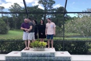 Man walks across pool patio with family members nearby