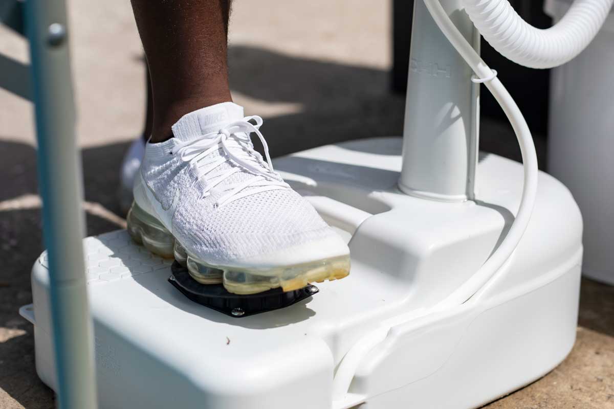 closeup of white sneaker applying pressure to foot pump