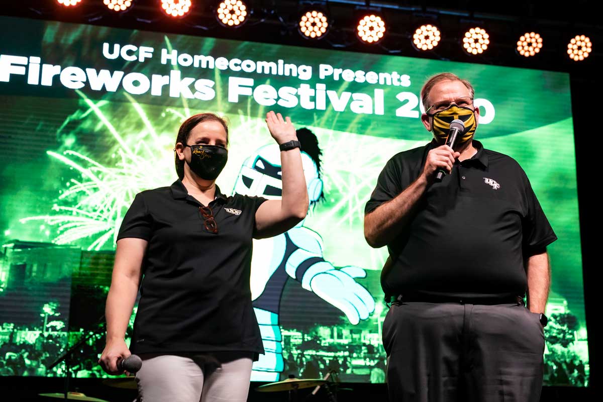 President Alexander N. Cartwright and First Lady Melinda Cartwright hold microphones on stage