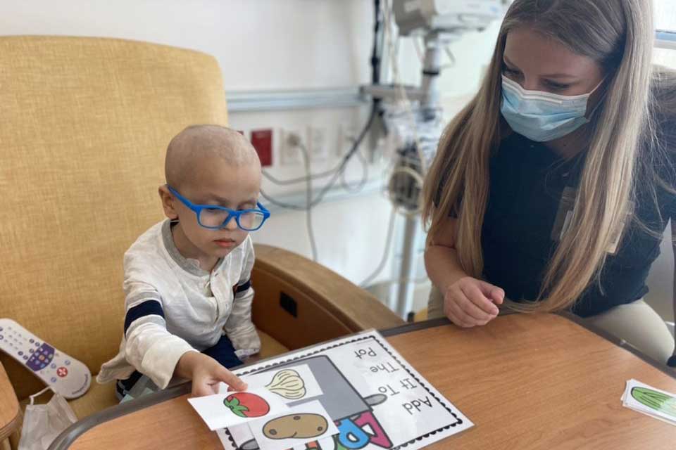 Lindsey Palm sits at the bedside of a young patient in the hospital