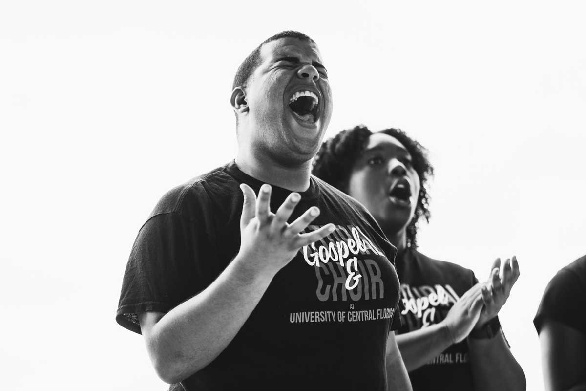 2 UCF students wearing gospel choir T shirts sing 