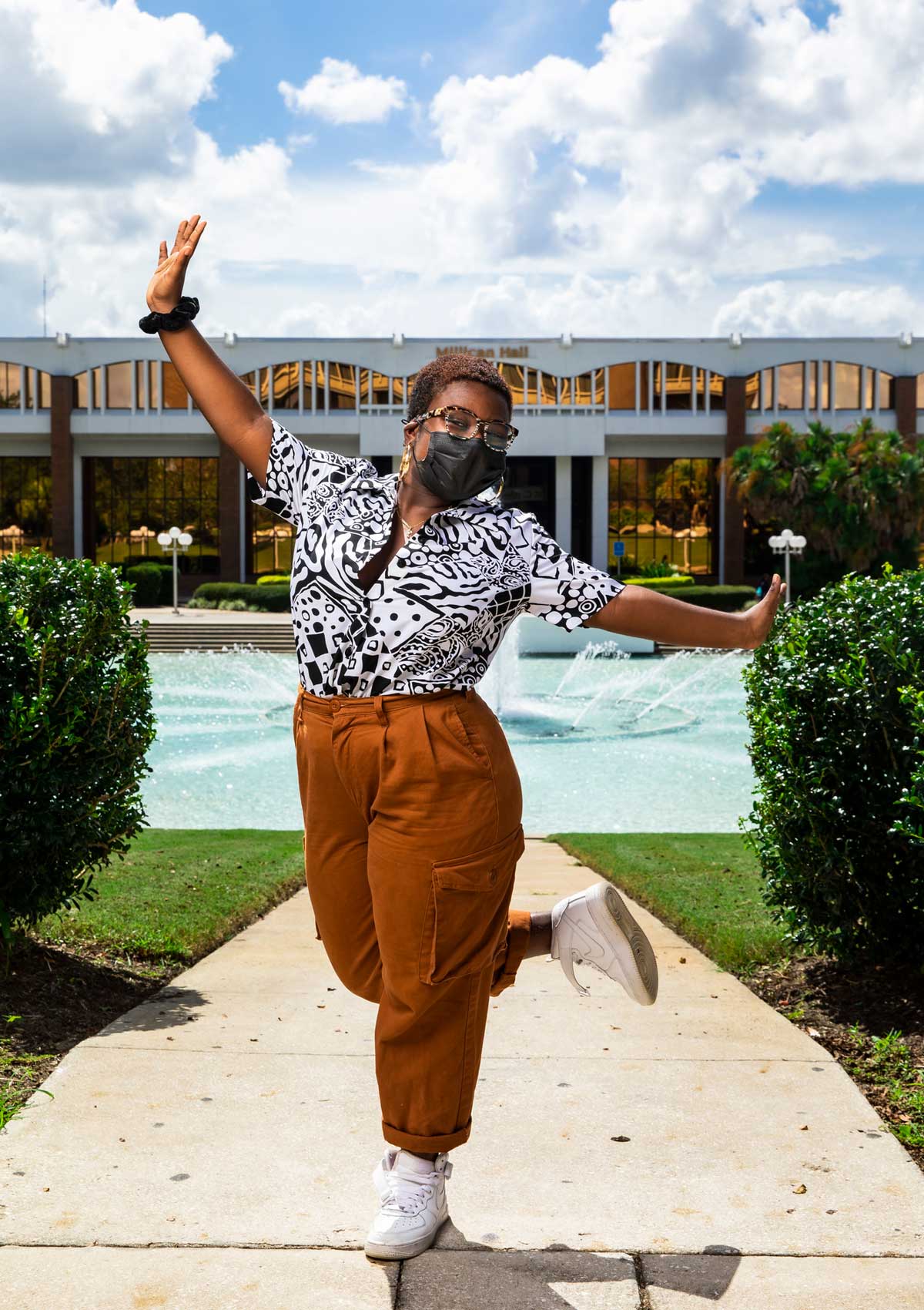 Keyuna Julien poses on one leg with arms outstretched in front of Reflecting Pond on sunny day