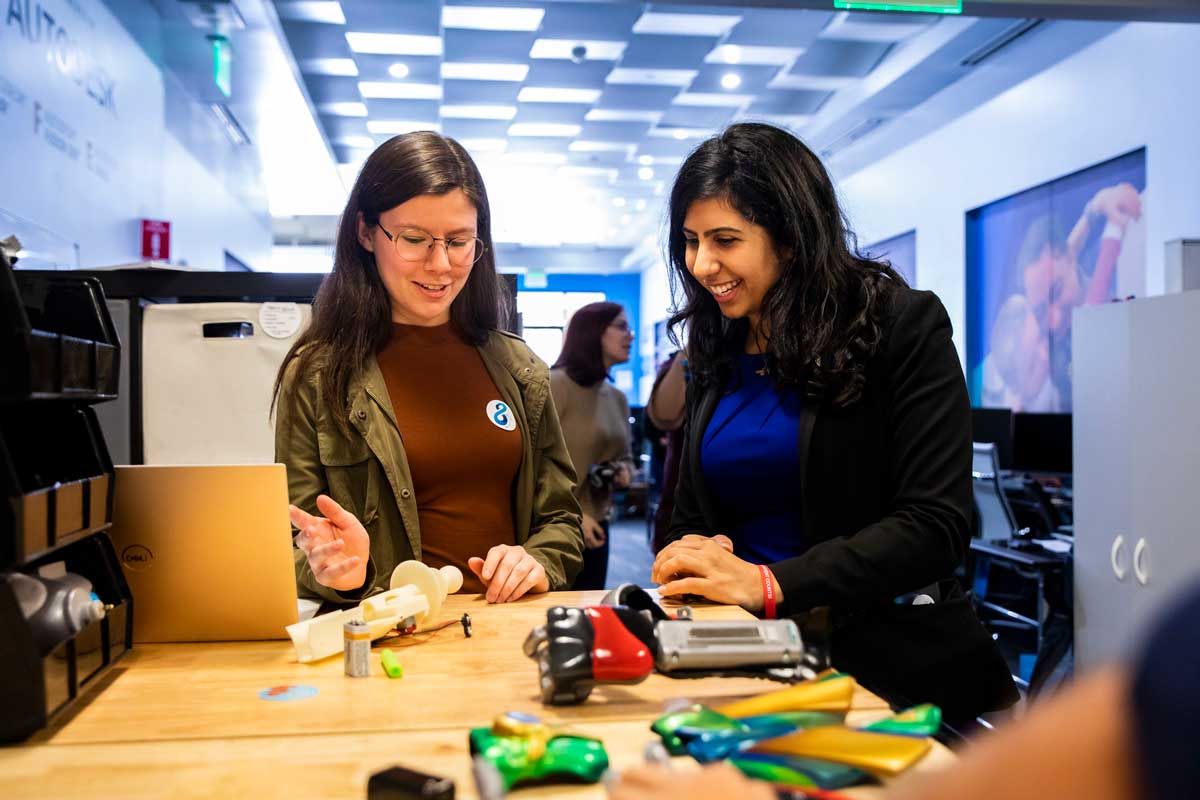 Anna Eskamani and UCF student look at 3D printed parts of a prosthetic limb on a table