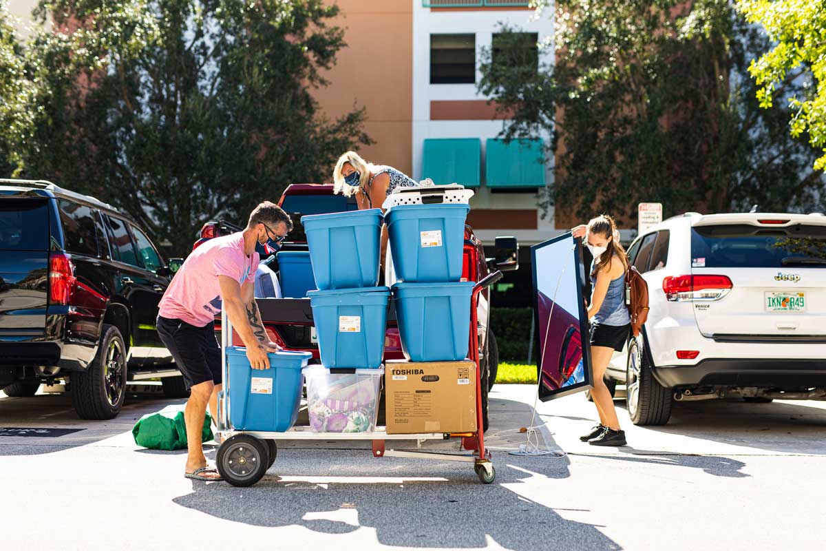 Parents help daughter move into UCF Housing, loading bins on a dolly in front of their car