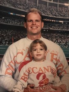 Young Joey and his father pose for a photo while wearing matching Bucs sweaters