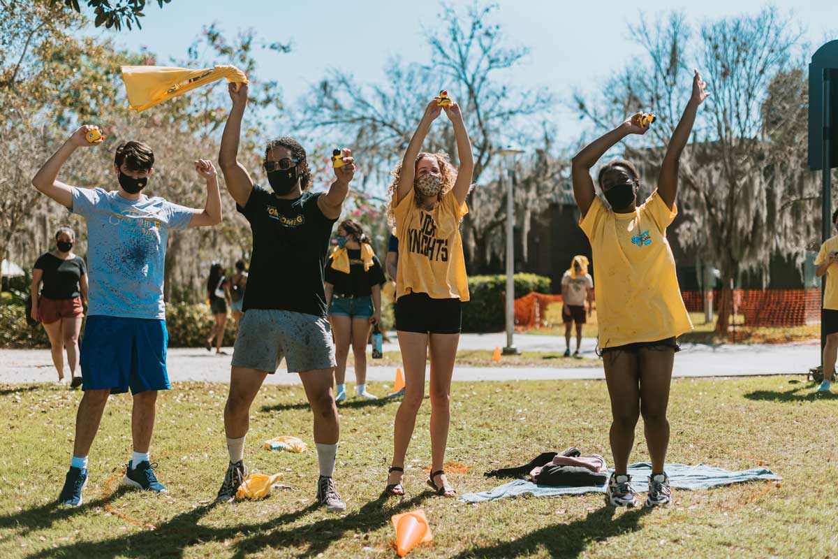 Four students wave their arms in the air