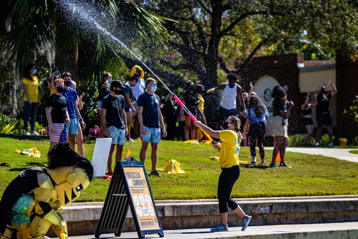 Woman sprays water soaker at crowd of students