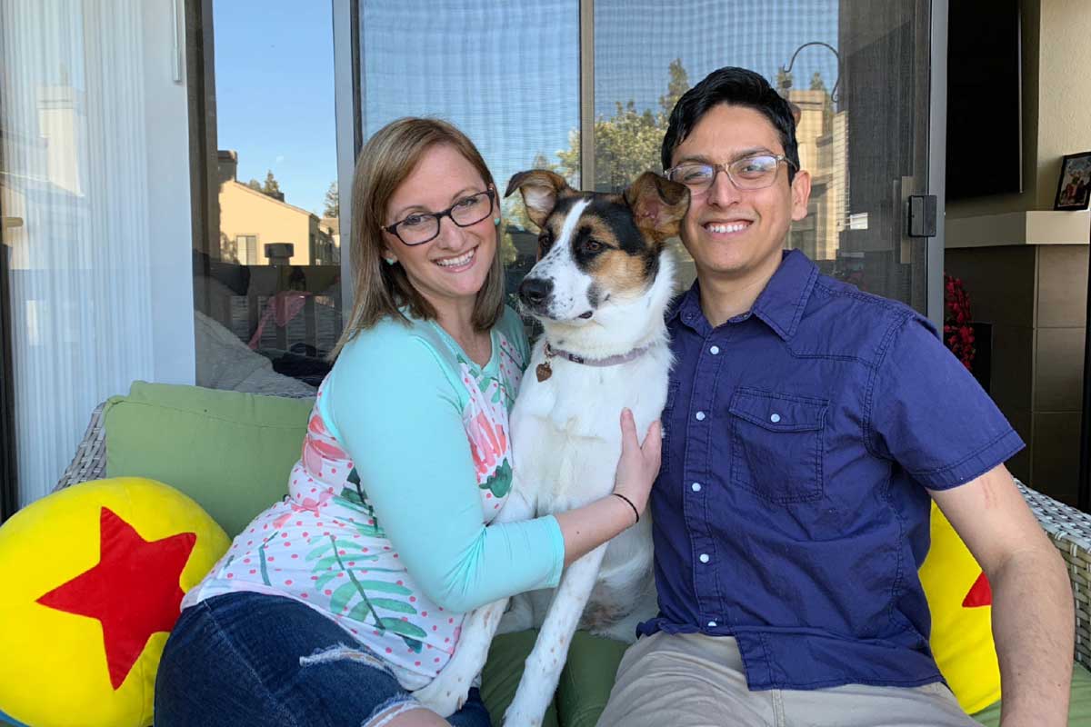 Teresa Falcone and Chris Sanchez sit on a couch outside with their dog, Violet