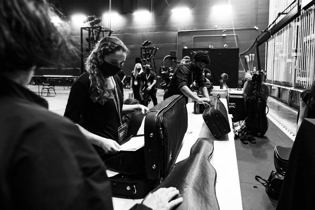 black and white photo of student unpacking instruments from their cases on a table backstage