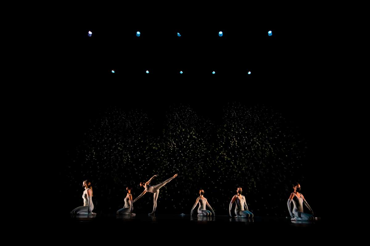 Six dancers on stage with a black starry backdrop behind them