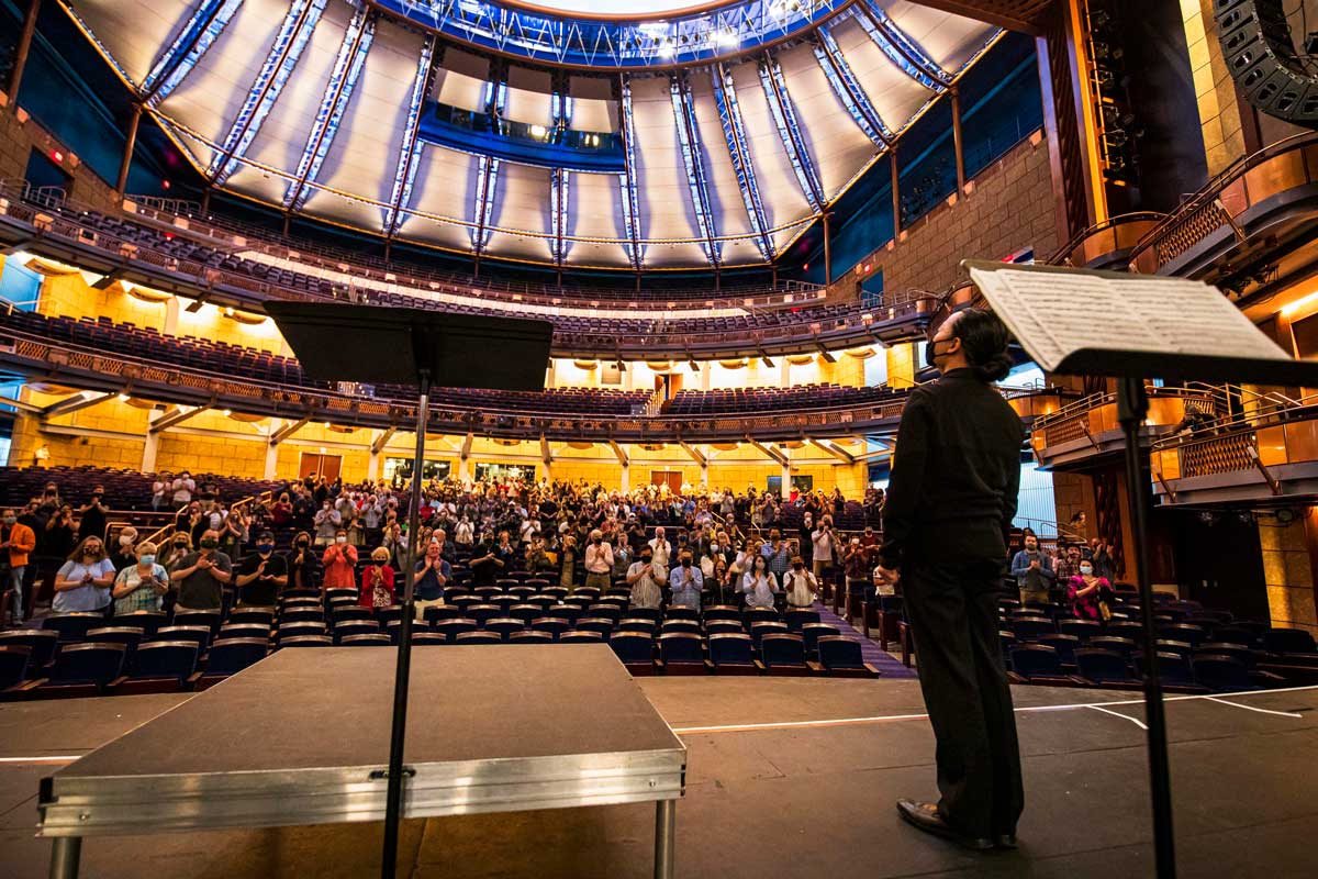 Wide shot of Dr. Phillips Center's stage; Chung Park faces crowd, in standing ovation