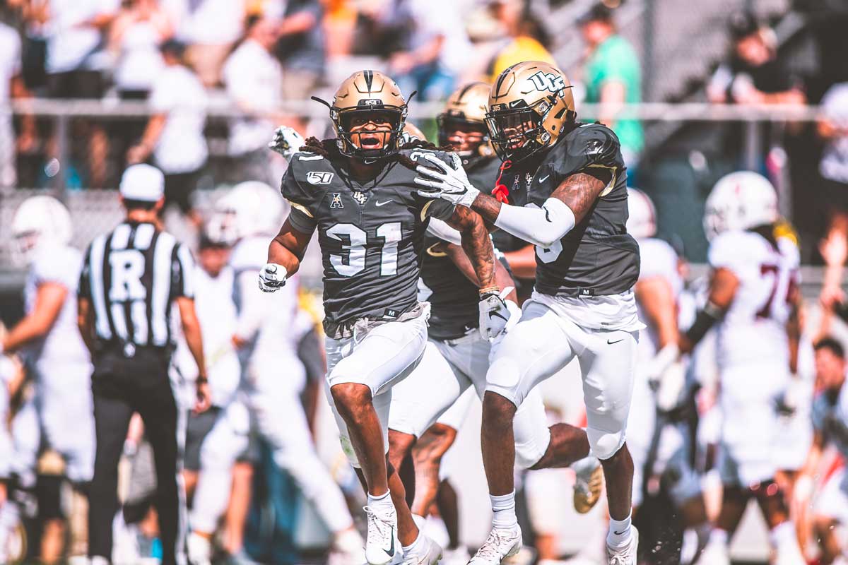 Aaron Robinson (#31) runs on field while wearing gold helmet and gray jersey with white pants