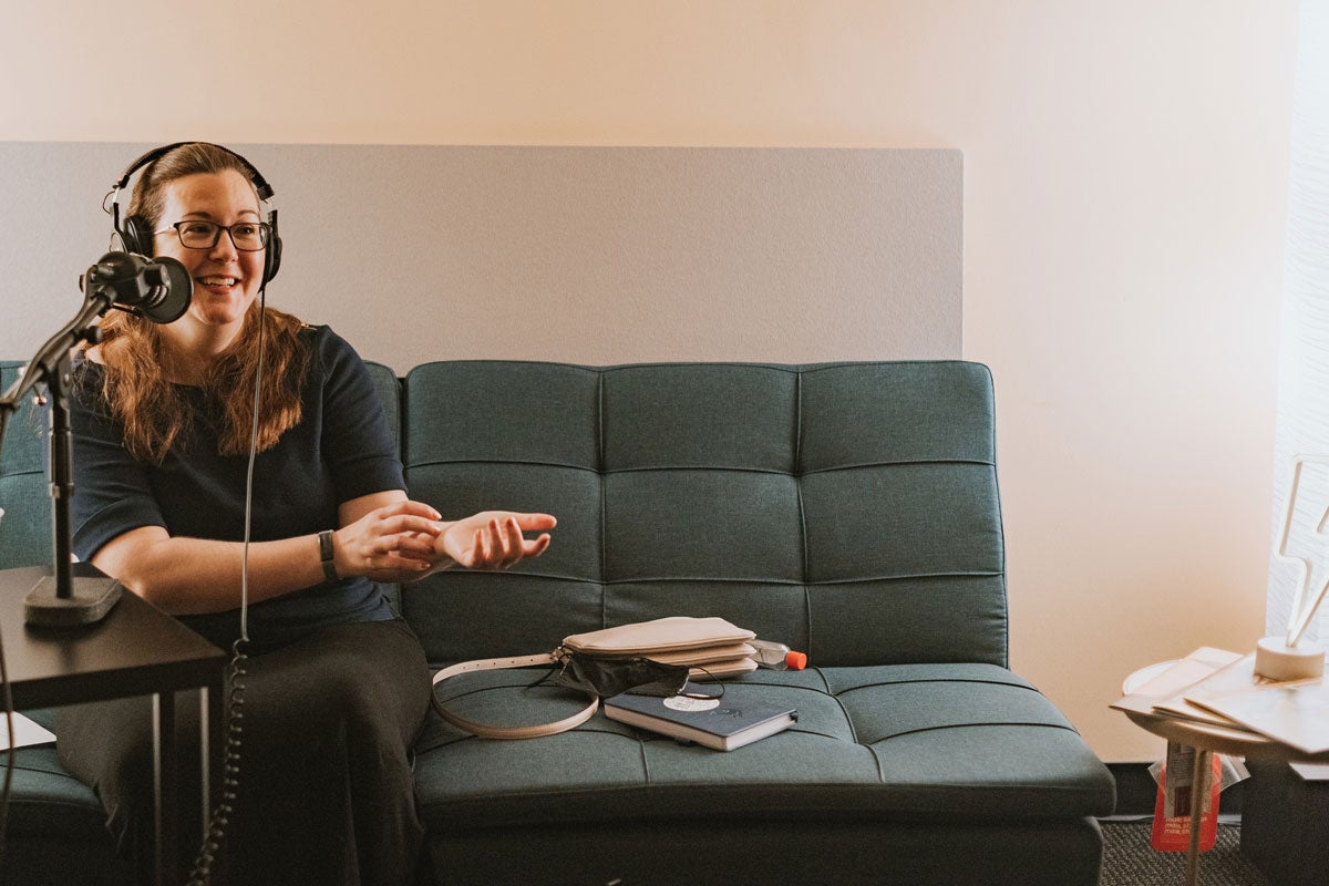 Claire Connolly Knox with headphones on sits on blue couch