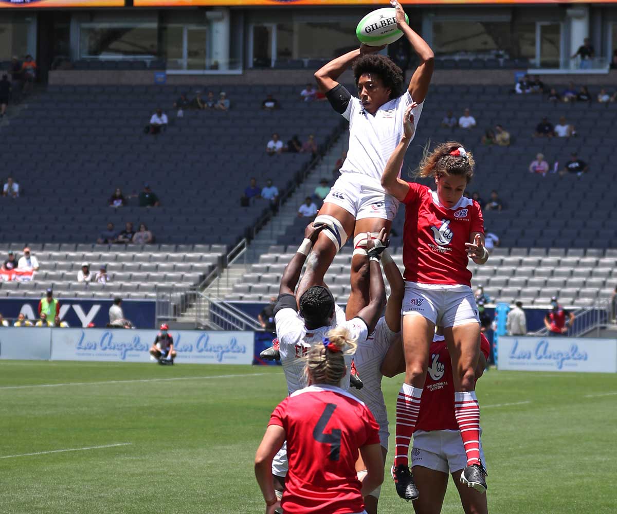 Kristen Thomas midair in a scrum of Rugby players