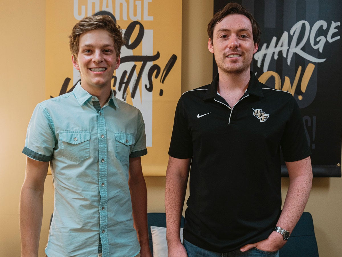 Daniel West and Alex Cumming stand in front of Go Knights Charge On signs