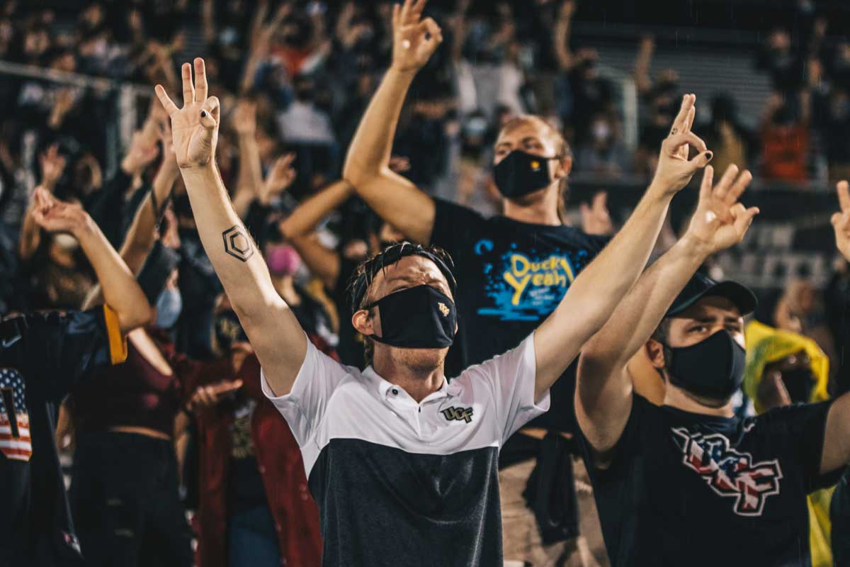 Fans wearing face masks with their arms raised 