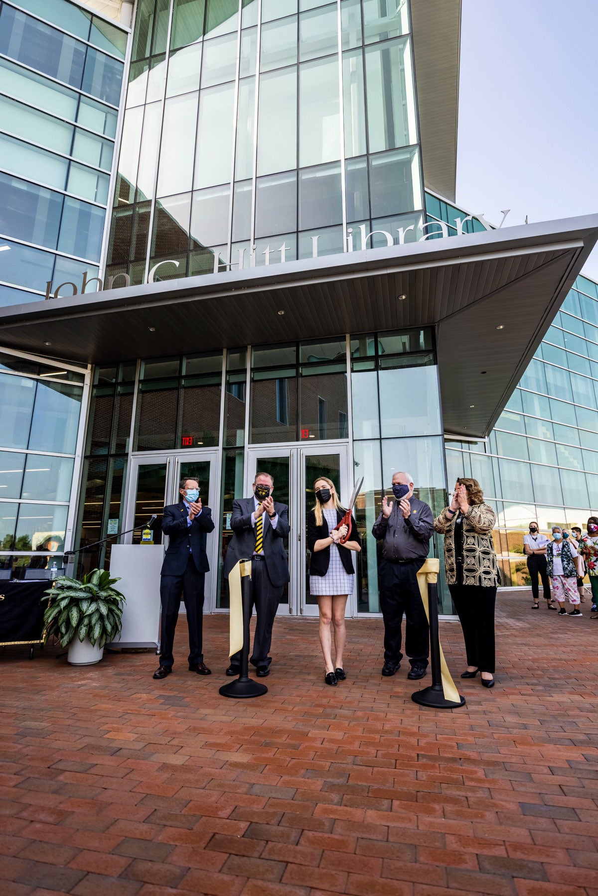 Five university leaders stand at the entrance of John C. Hitt Library after cutting a ribbon for grand opening