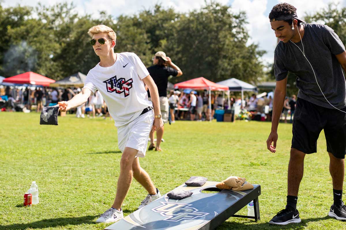 Two male students play cornhole