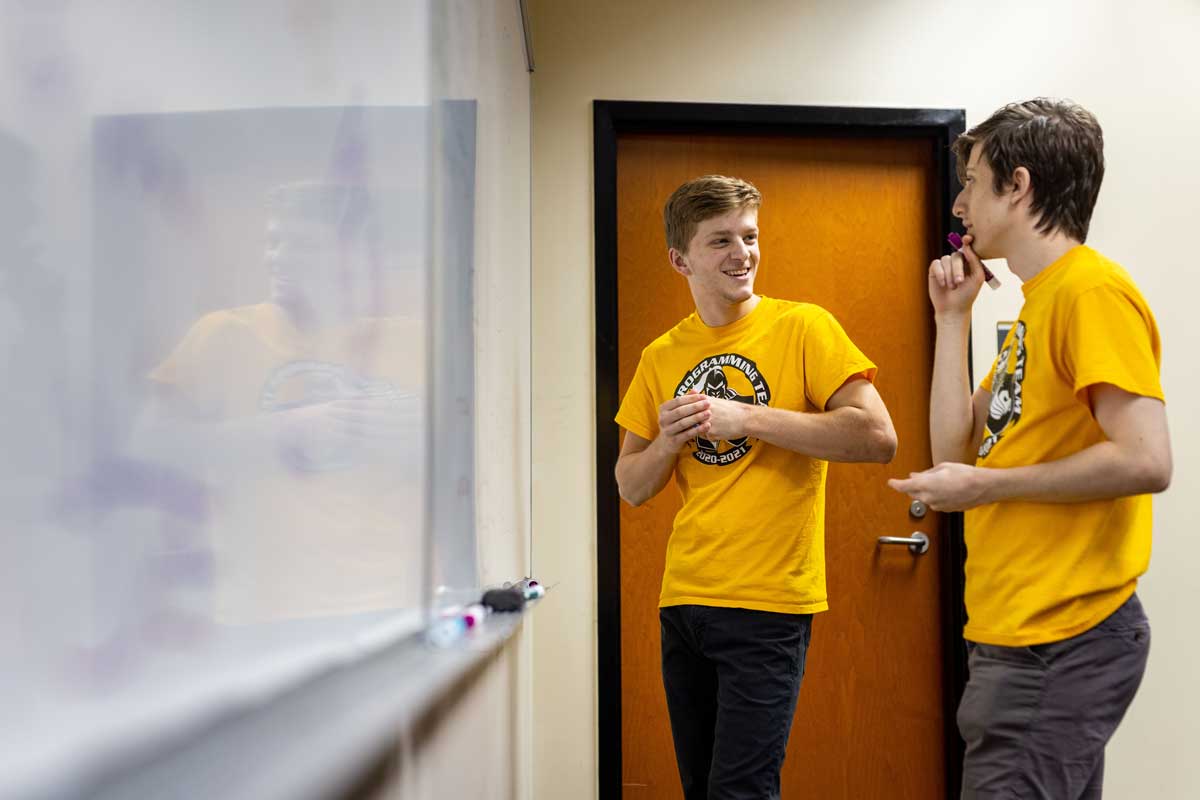 Daniel West and Sharon Barak discuss a problem at a white board