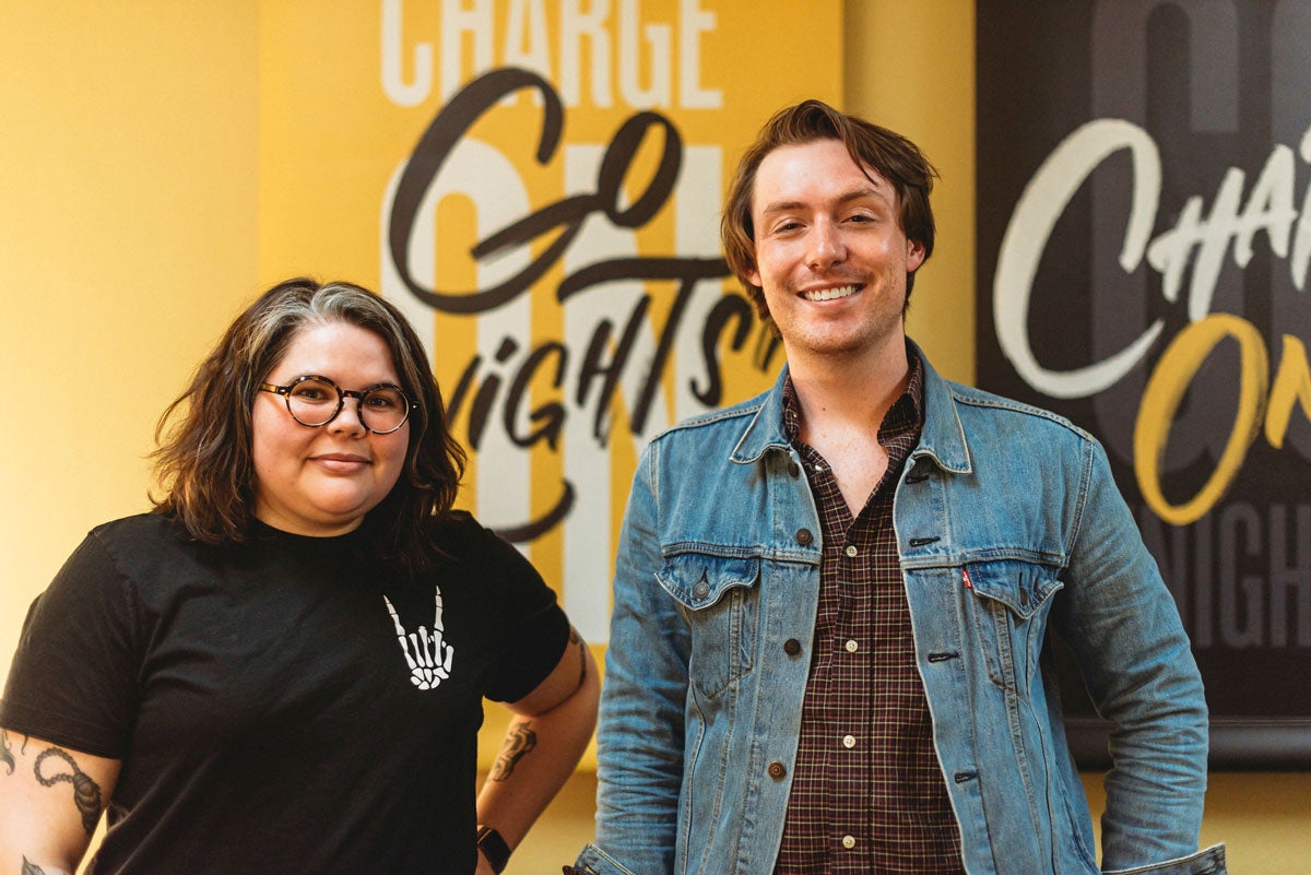 Reina Castellanos and Alex Cumming in front of Go Knights Charge On black and gold wall banners