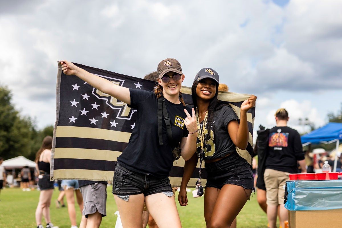 Two women pose with a UCF flag on Memory Mall